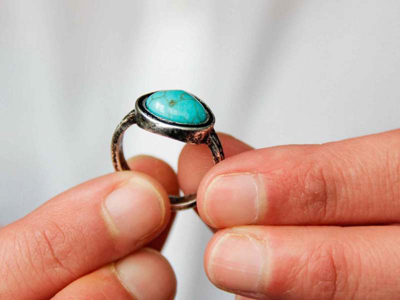 Mann h&auml;lt einen gro&szlig;en Ring mit einem t&uuml;rkisfarbenen Stein in der Hand.