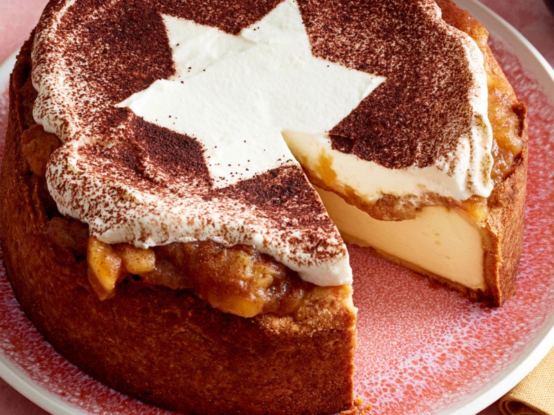 K&auml;sekuchen mit Bratapfel-Topping, Sahneschicht und Kakaopulver.