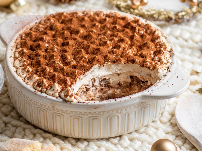 Tiramisu in wei&szlig;er Auflaufform auf weihnachtlich gedecktem Tisch.