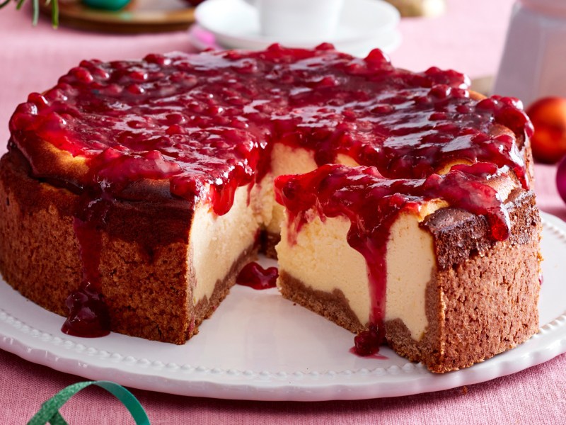K&auml;sekuchen mit Preiselbeer-Topping auf einem wei&szlig;en Teller.