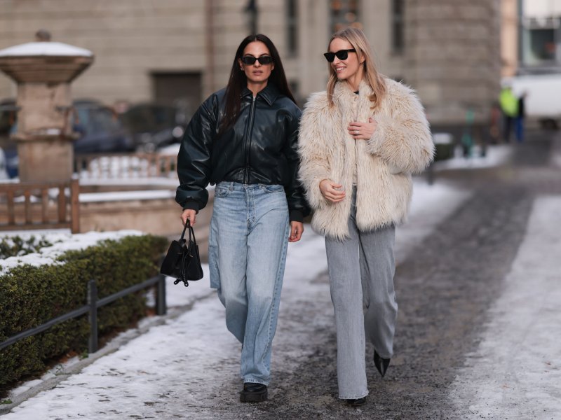 Zwei Influencerinnen, die weite Hosen tragen und durch den Schnee laufen.