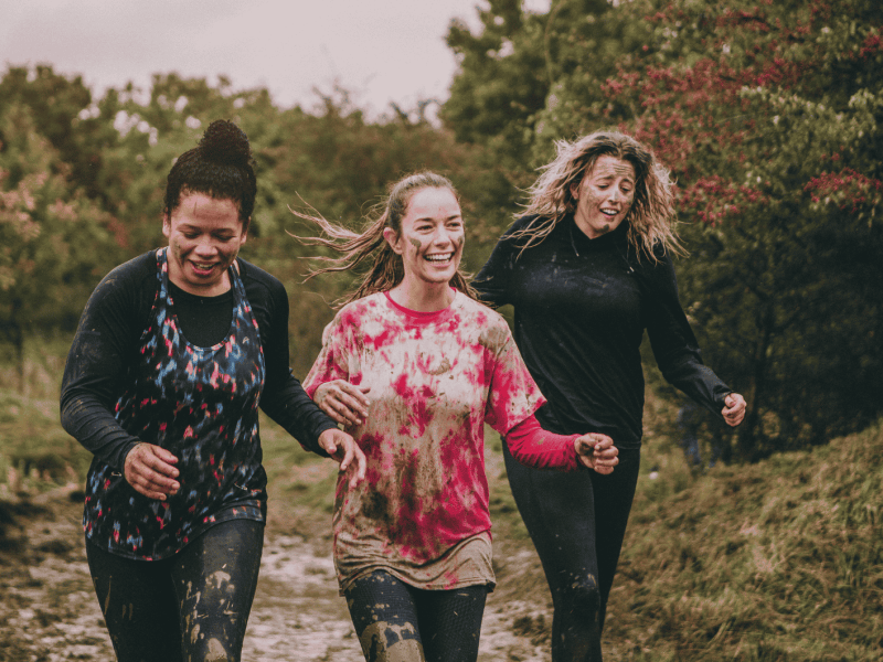 Glückliche Frauen laufen Hindernisparcours mit