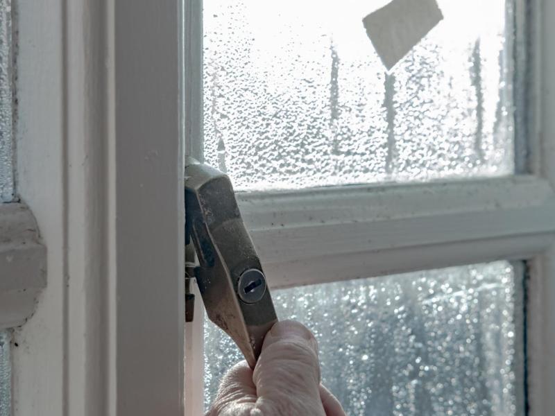 Person öffnet ein Fenster im Regen.