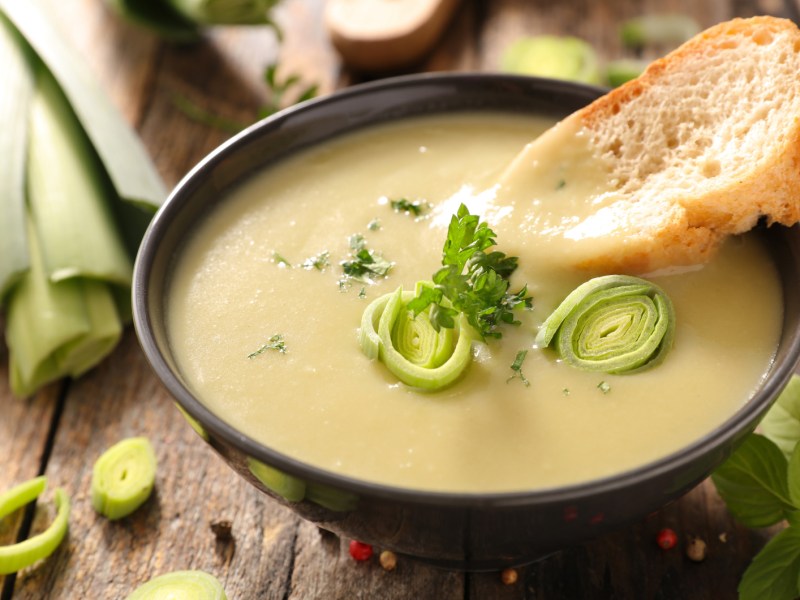 Cremige Suppe mit Kartoffeln und Lauch in einer schwarzen Suppenschale.