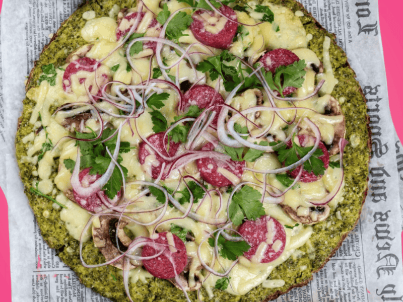 Brokkoli Pizza auf pinkem Untergrund.