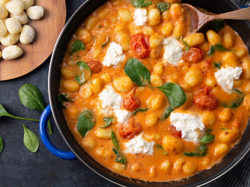 Gnocchi mit Baslikum, Tomatensoße und Käse in einem großen Topf.