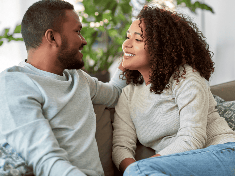 Frau und Mann sitzen auf dem Sofa und l&auml;cheln sich an