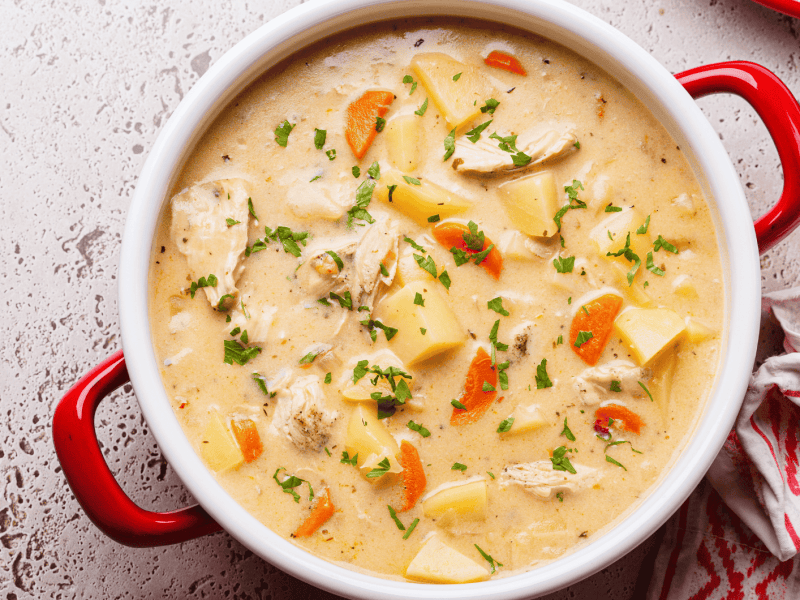 H&uuml;hnersuppe mit Sahne, Kartoffeln und M&ouml;hren in gro&szlig;em Topf.