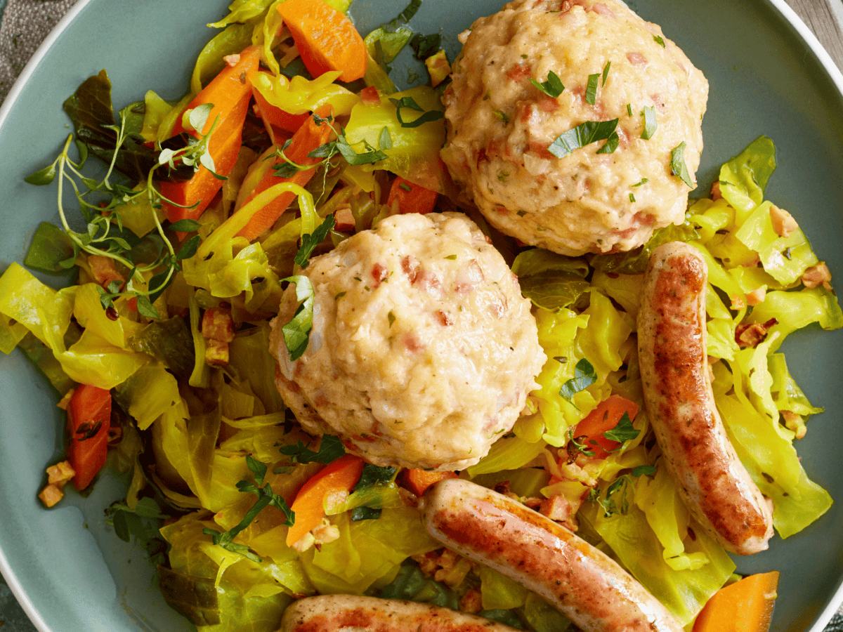 Speckknödel auf Weißkohl mit nürnberger Würstchen.