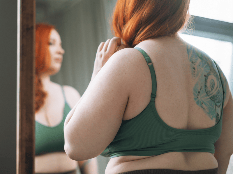 Frau mit hohem BMI steht vor dem Spiegel