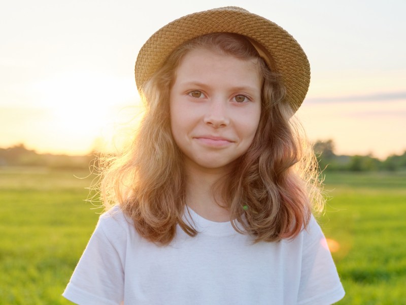 M&auml;dchen, ca. 10 Jahre alt, an einem Sommerabend auf einer weitl&auml;ufigen Wiese.
