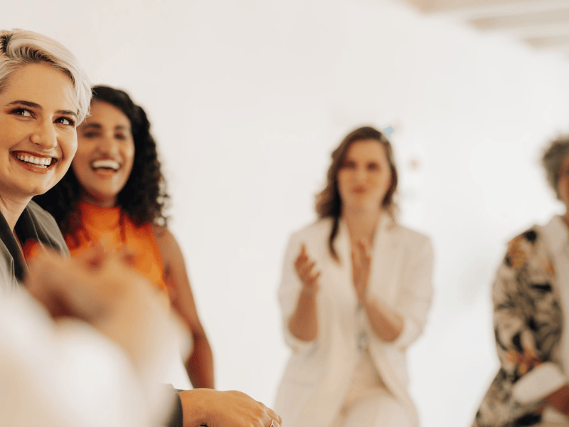 Mehrere Frauen sitzen zusammen und lachen.