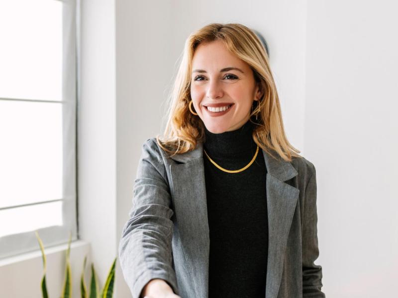 Junge blonde Frau mit grauem Blazer.