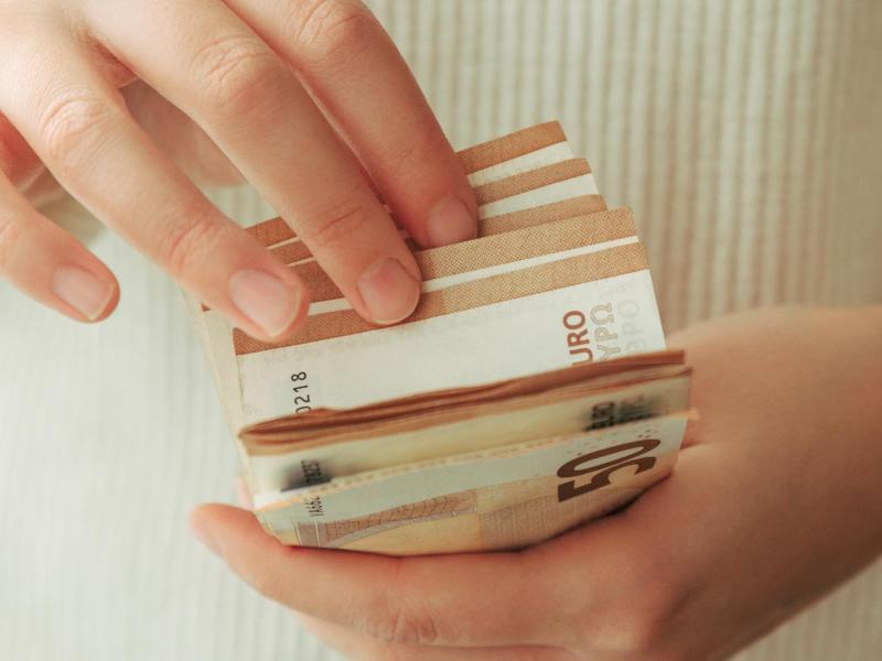 Frau mit hellem Pulli z&auml;hlt 50-Euro-Scheine.