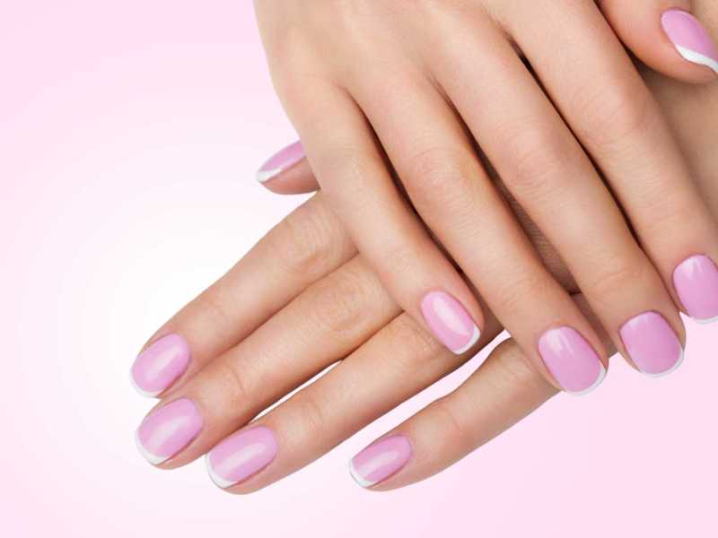 Nägel mit French Design vor einem rosa Hintergrund