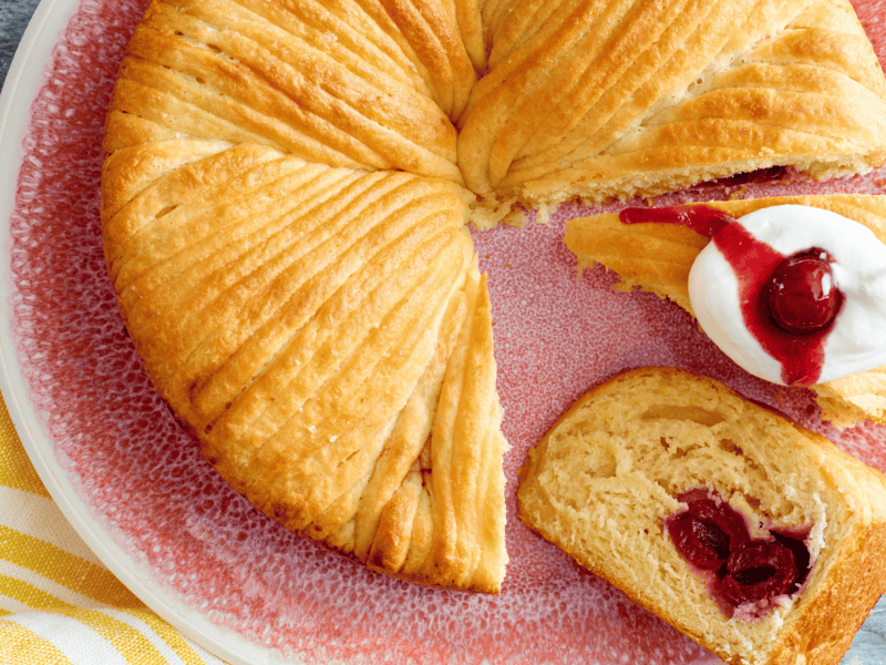 Wollknäuel Kuchen mit Kirschen auf einem rosa-farbenen Teller.