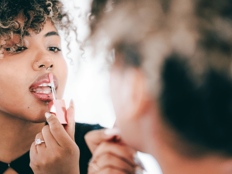Frau tr&auml;gt ihren rosafarbenen Lipgloss auf.