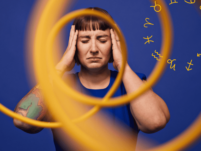 Frau vor blauem Hintergrund hinter gelber Spirale h&auml;lt sich mit geschlossenen Augen den Kopf