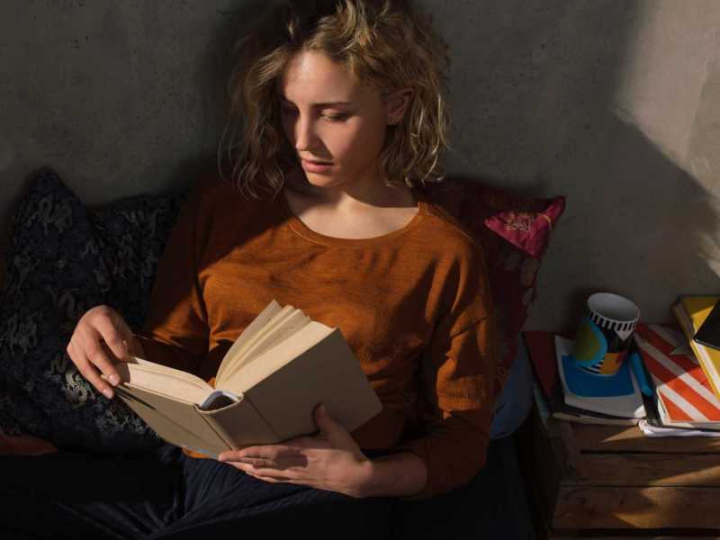 Blonde Frau liest einen Thriller im Freien. Dunkle Atmosph&auml;re.