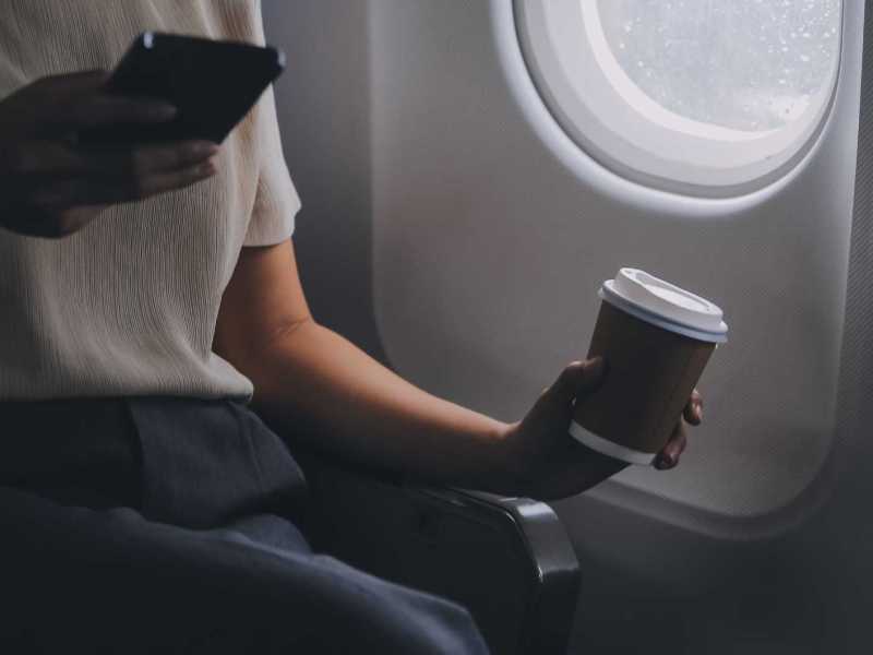 Frau im Flugzeug trinkt einen Kaffee