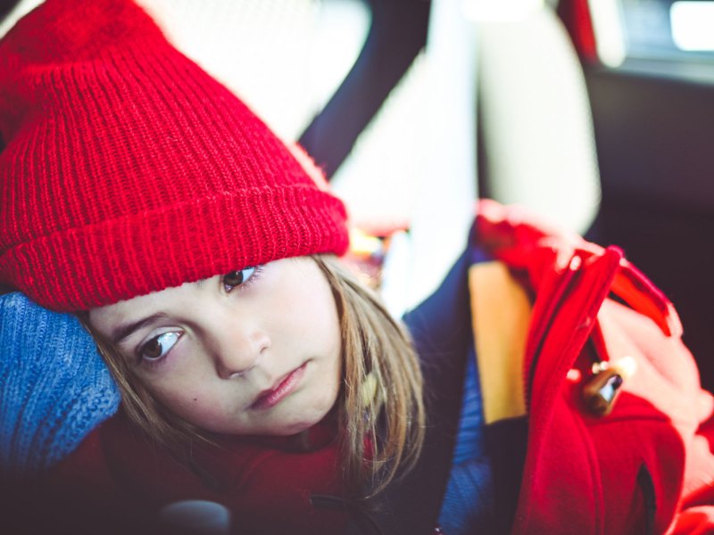 M&auml;dchen sitzt m&uuml;de im Auto.