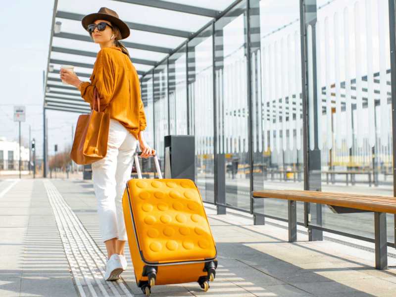 Junge Frau am Flughafen mit gelbem Koffer.