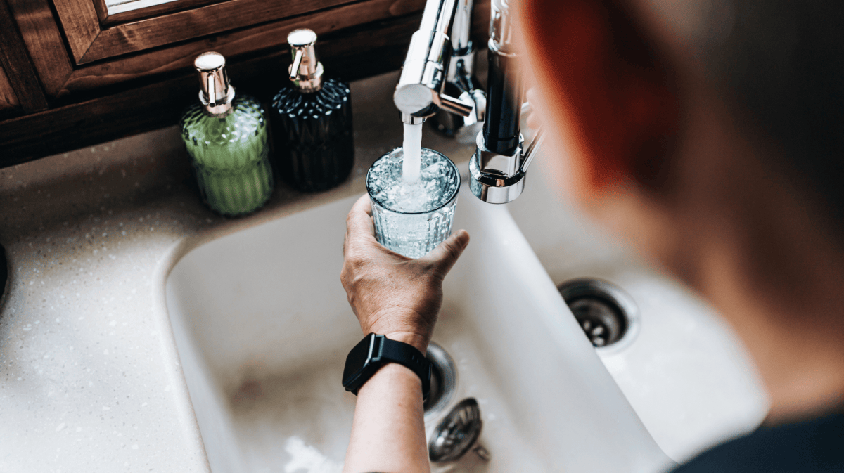 Mann füllt Wasser aus Hahn in Glas.