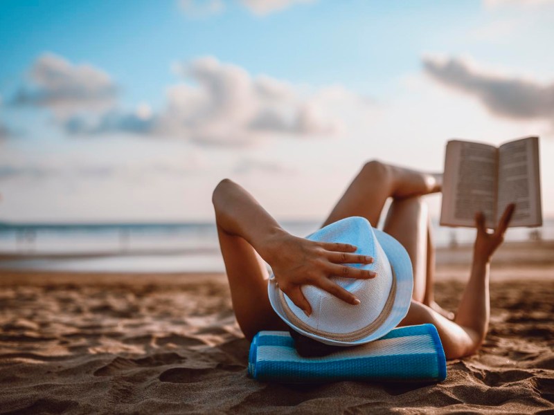 Frau liest entspannt am Strand