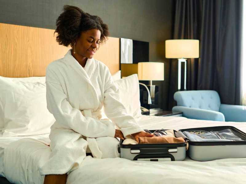 Junge Frau sitzt auf dem Hotelbett.