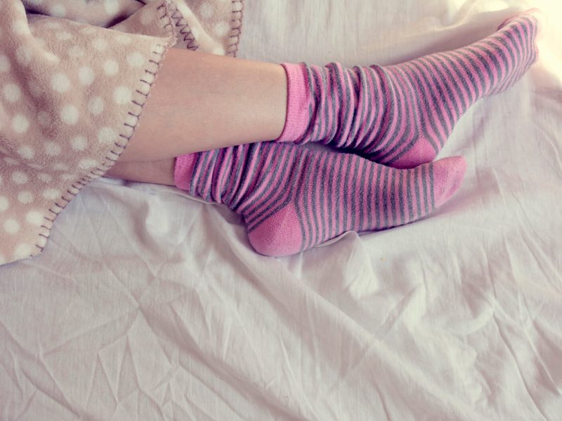 Junge Frau schl&auml;ft mit rosa gestreiften Socken