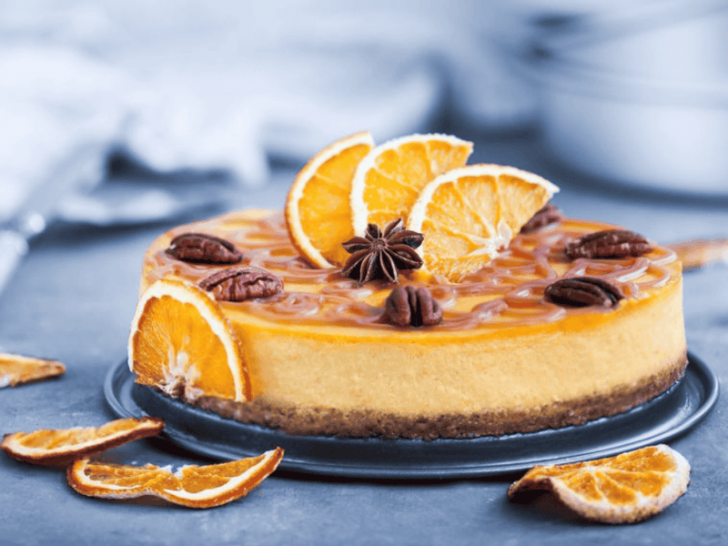 Orangen-Cheesecake mit Sternanis auf einem blauen Tischtuch.