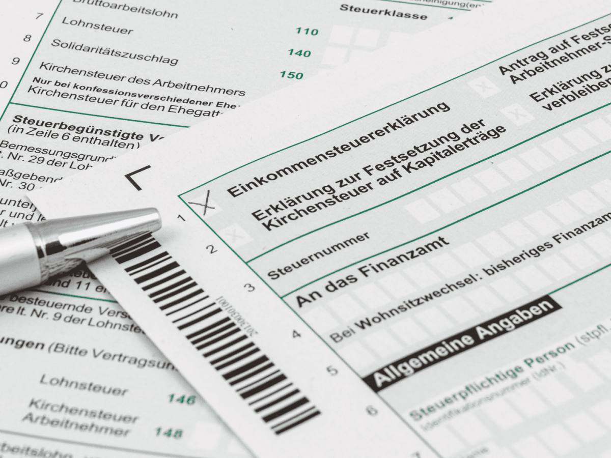Steuerformulare liegen auf Tisch, ein Kulli daneben.