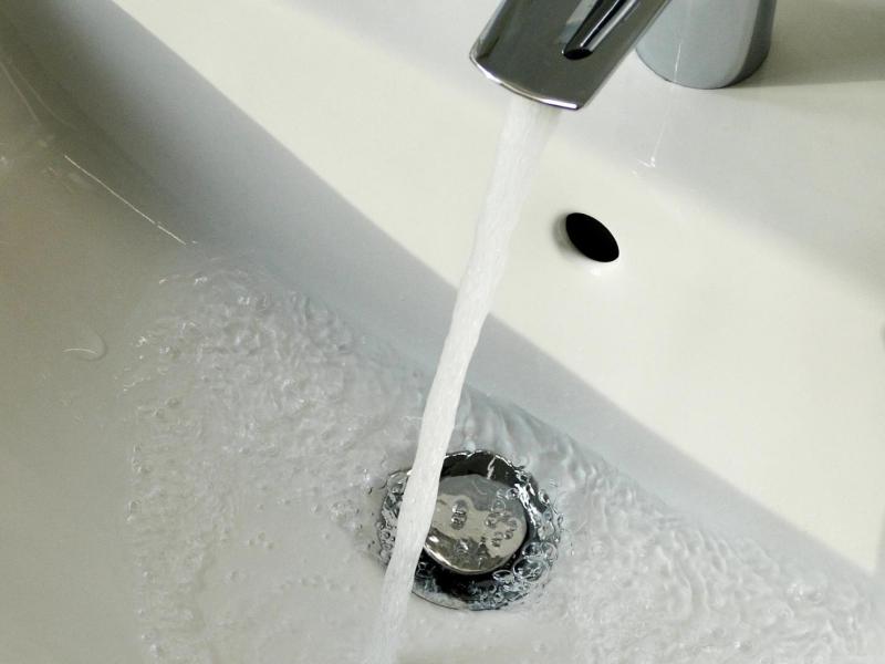 Wasser flie&szlig;t aus dem Wasserhahn am Waschbecken im Badezimmer.