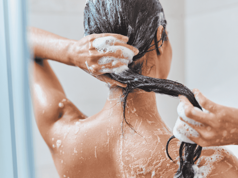Frau w&auml;scht ihre Haare nach Shampoo aus.
