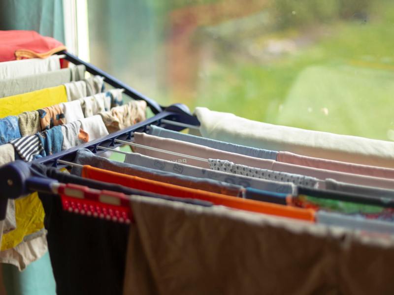 W&auml;schest&auml;nder mit bunter Kleidung steht in einer Wohnung