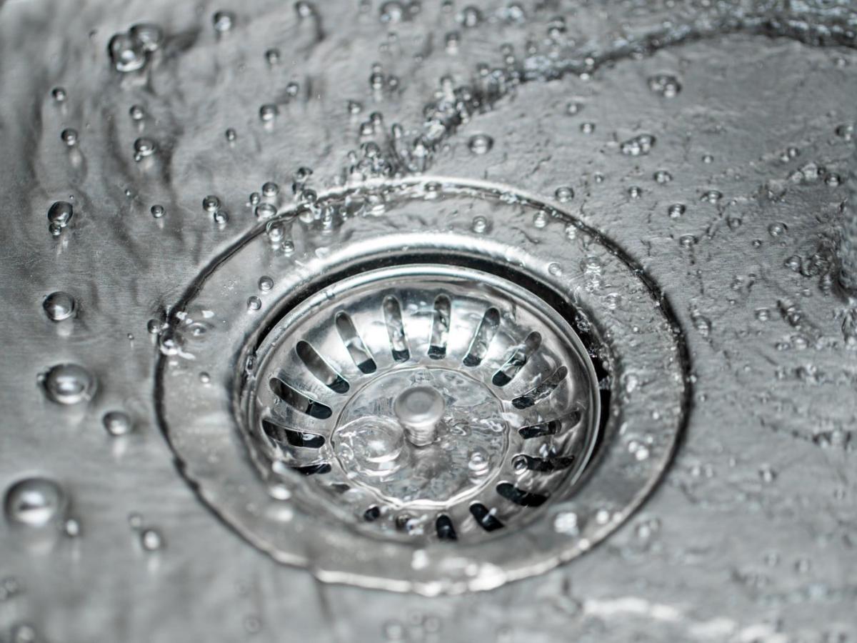 Wasser fließt in den Abfluss eines Edelstahlspülbeckens.