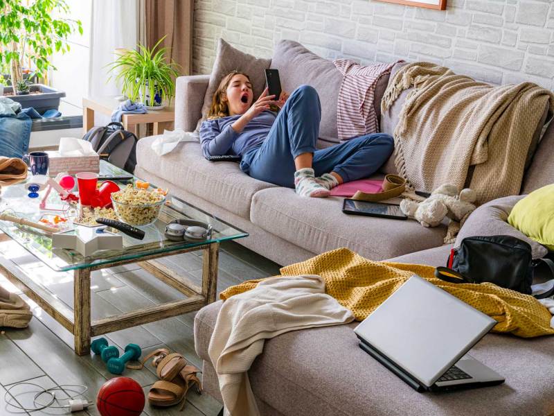 Teenagerm&auml;dchen liegt auf dem Sofa, um sie herum herrscht Chaos.