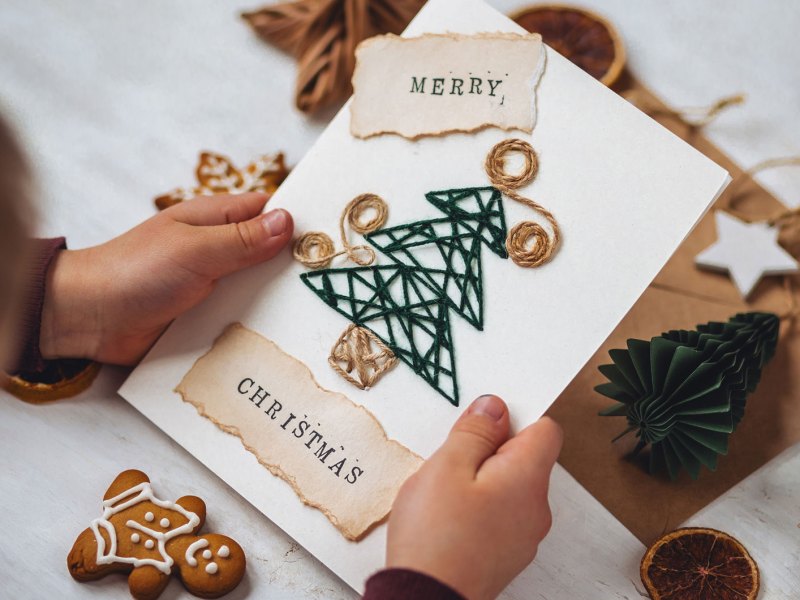 Kinderh&auml;nde halten eine selbst gebastelte Weihnachtskarte.