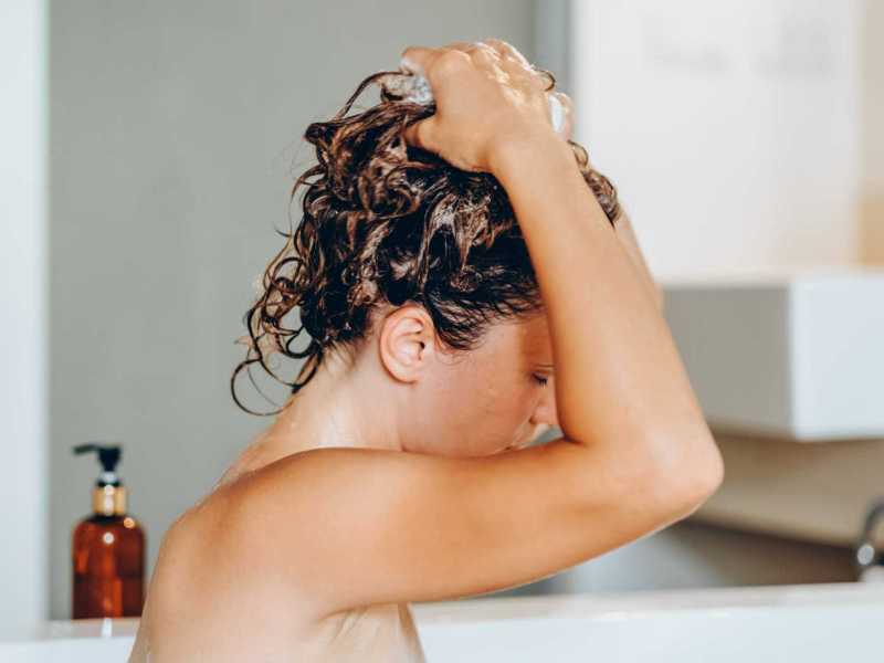 Aufnahme einer Frau, die sich in der Badewanne die Haare shampooniert.