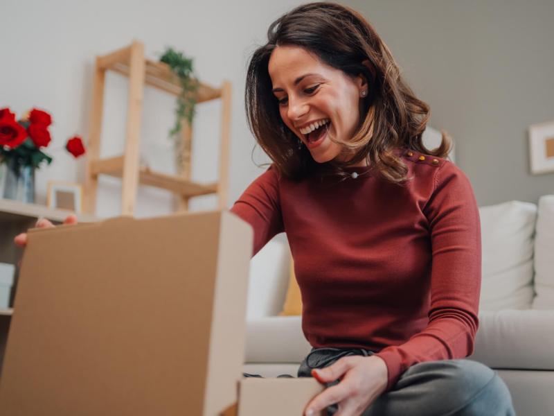 Frau packt ein Geschenk aus und freut sich riesig.