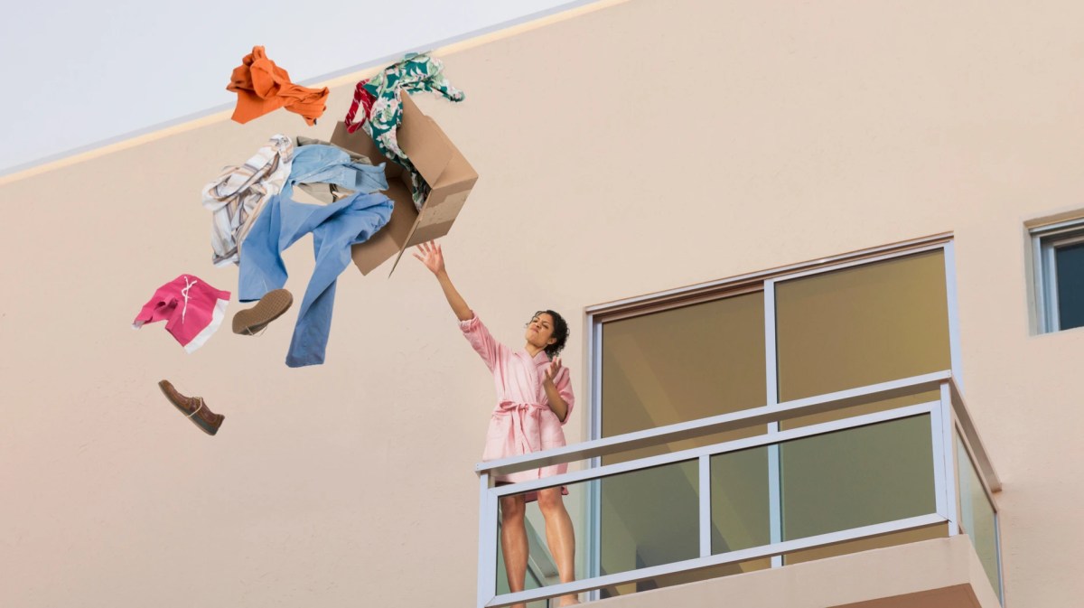 Frau wirft Kleidung vom Balkon