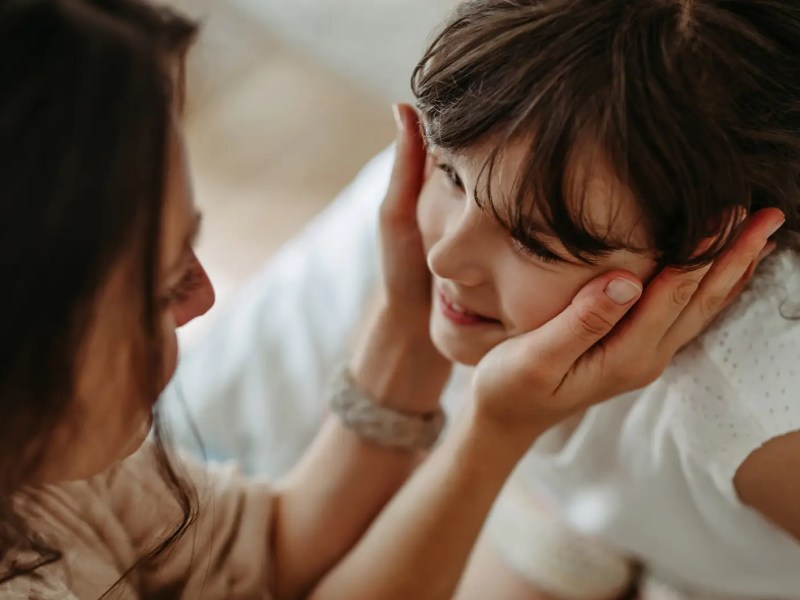Mutter h&auml;lt das Gesicht ihrer Tochter, ca. 8 Jahre alt, in den H&auml;nden.