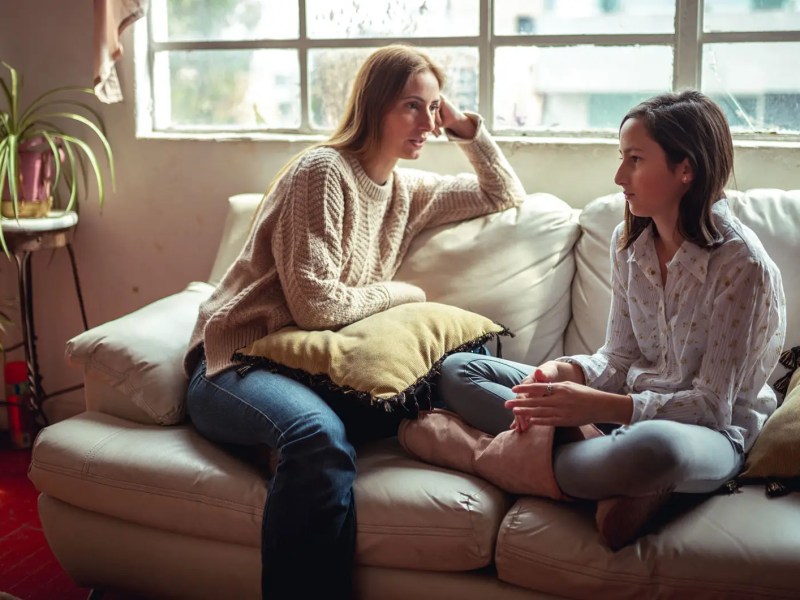 Mutter und Tochter bei einem ernsten Gespr&auml;ch, beide sitzen auf der Couch.