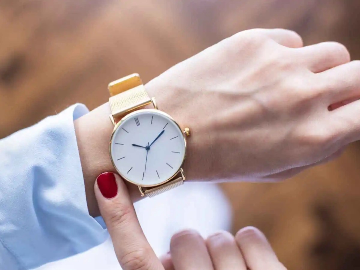 Eine Frau trägt eine Uhr am Handgelenk und hält einen Finger daneben.