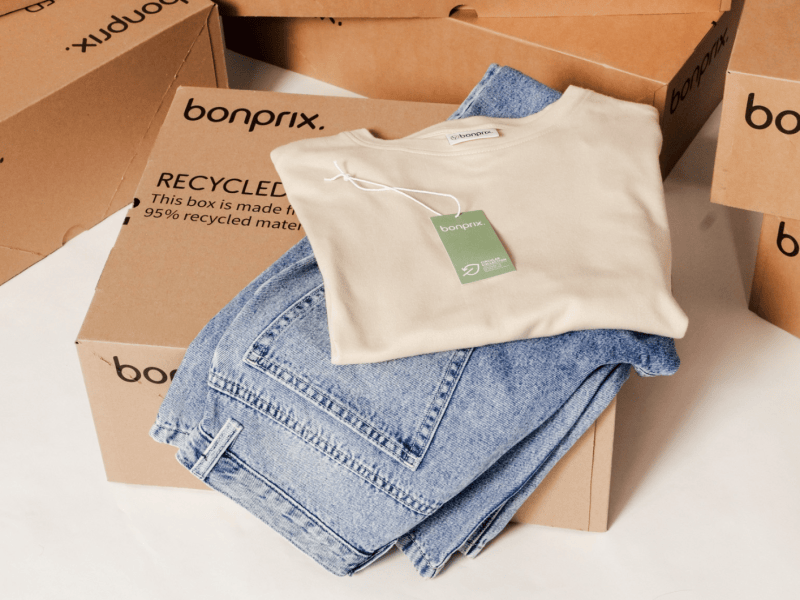 Jeans und Shirt vor Kartons mit Bonprix Logo